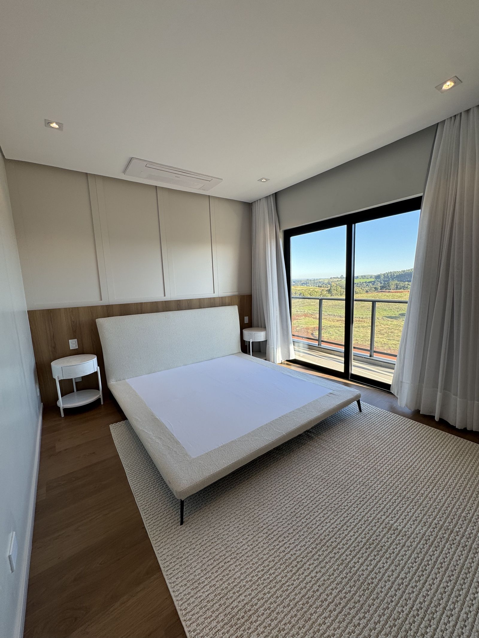 Suíte master com cama de casal e vista para o condomínio